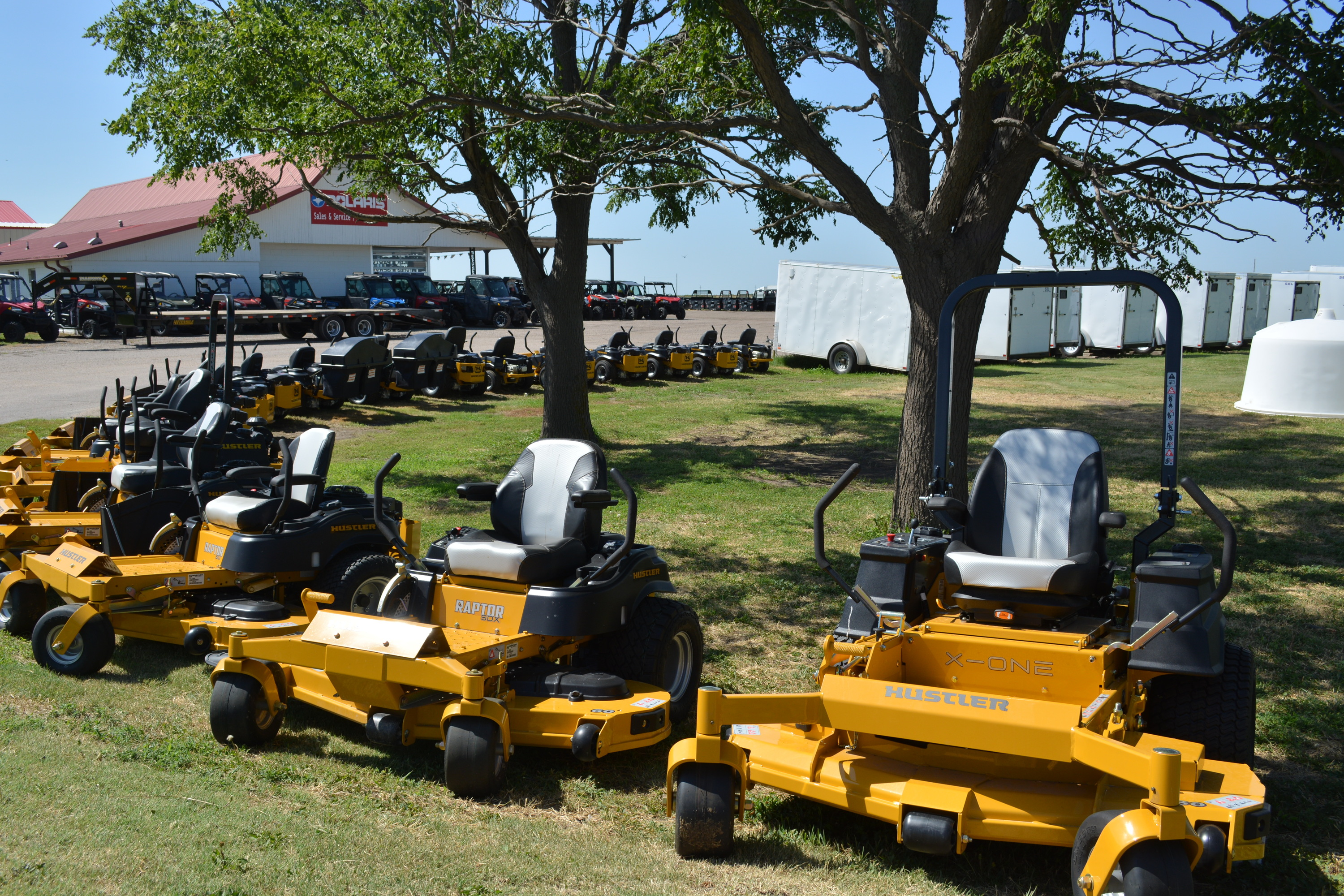 A lot of Hustler Lawn Mowers all parked right next to each other.